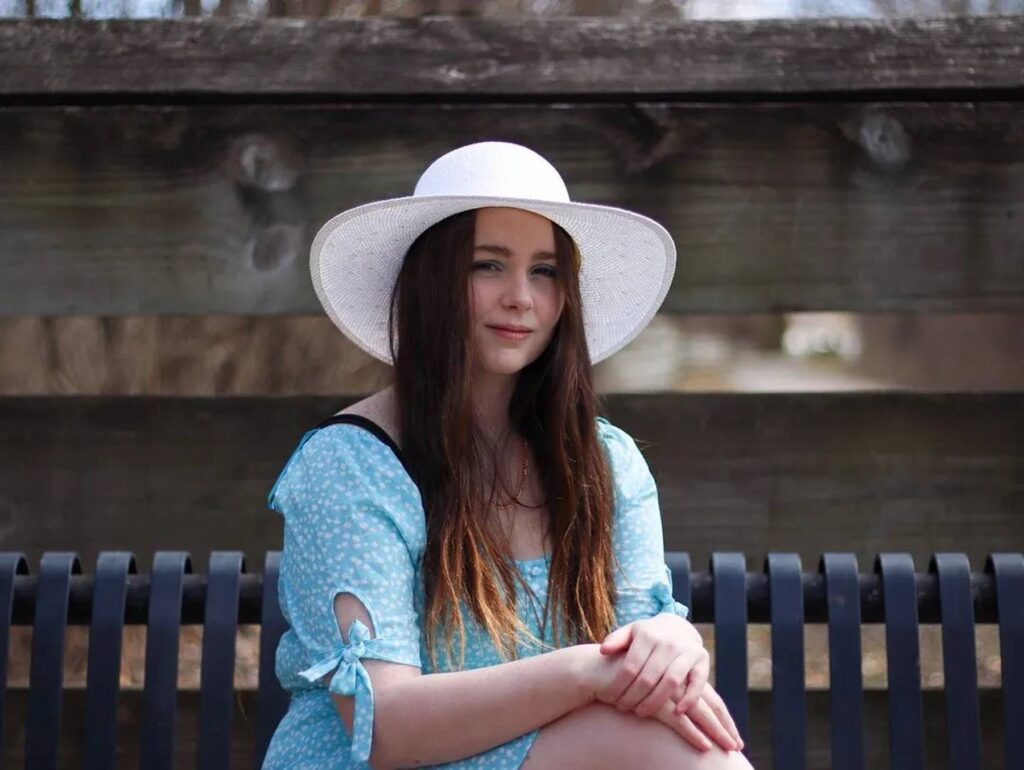 woman in blue sits on a park bench